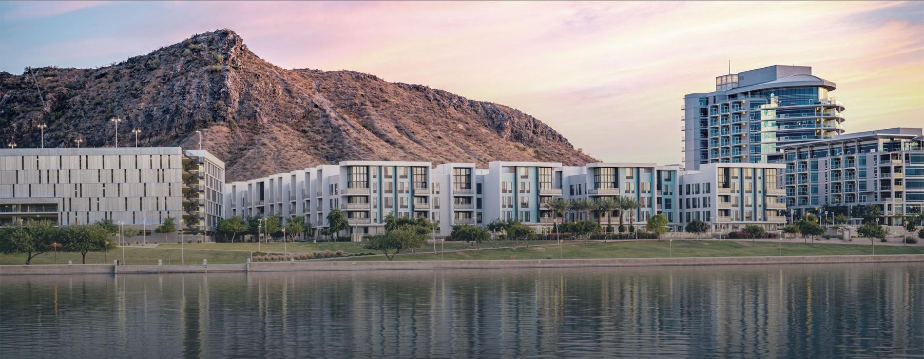 a body of water with buildings and a hill in the background