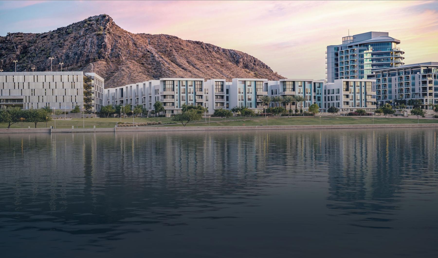 a body of water with buildings and a hill in the background